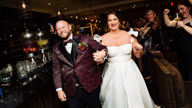 Newlyweds celebrating, with the groom in a patterned burgundy jacket