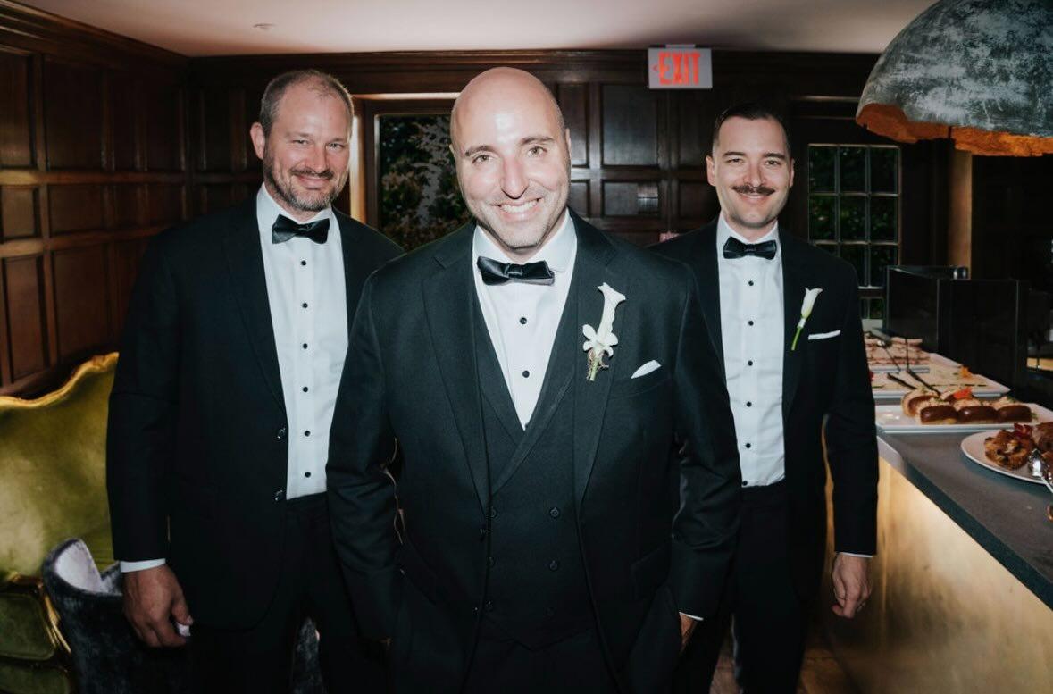 Three men wearing formal tuxedos at a wedding